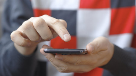 Closeup hands of a man using smartphone. He is typing message on mobile phone.の写真素材