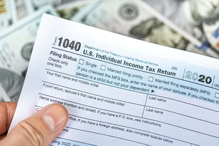 One hundred dollar bills and US 1040 tax form.