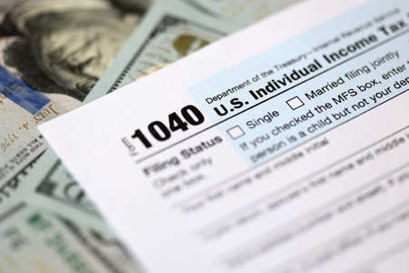 One hundred dollar bills and US 1040 tax form.の写真素材