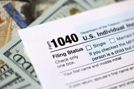 One hundred dollar bills and US 1040 tax form.の写真素材