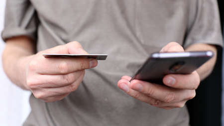 Young man using his phone holding credit cardの写真素材