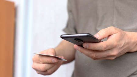 Young man using his phone holding credit cardの写真素材