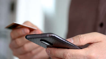 Young man using his phone holding credit cardの写真素材