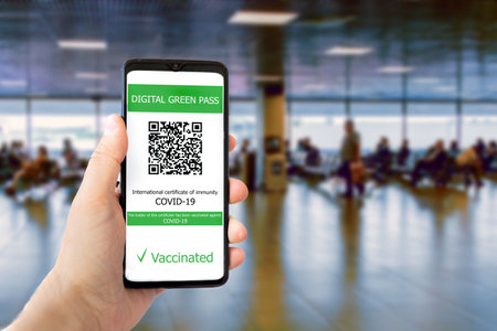The digital green pass with the QR code on the screen of a mobile in a man hand