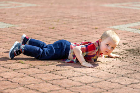 Cute toddler boy fell on park roadの写真素材