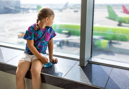 Child at the airport near the window is looking at airplanesの写真素材