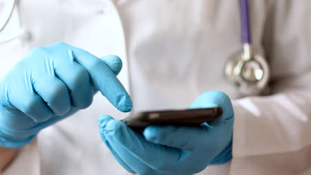 Male hands of medicalc doctor typing SMS message on smart phone.