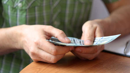 Hands counting US Dollar bills or paying in cash on money background.