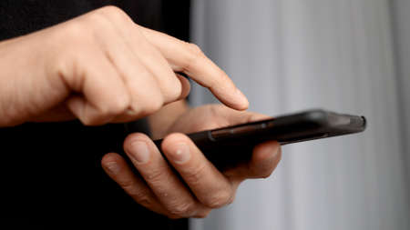 Close-up hands of unrecognizable man typing online message using smart phoneの写真素材