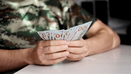 Hands counting US Dollar bills or paying in cash on money background.の写真素材