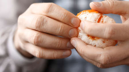 Close-up hands are peeling orange and tasty tangerine.の写真素材