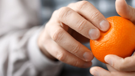 Close-up hands are peeling orange and tasty tangerine.の写真素材