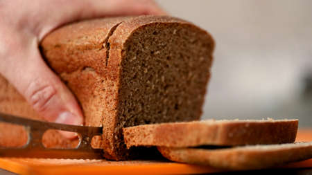 Slicing whole bread on cutting board.