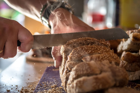 Isolated close up of a baker cutting a fresh steaming loaf of bread- Israelの写真素材
