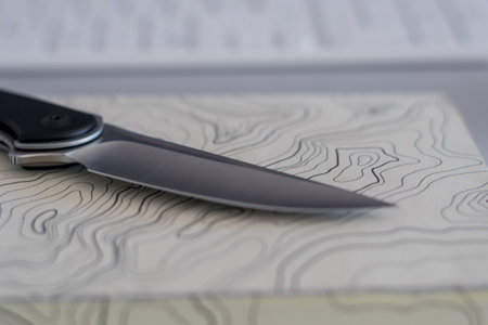 Isolated close up of a single blade knife on a topographic map notebook- Concept camping/ outdoors...