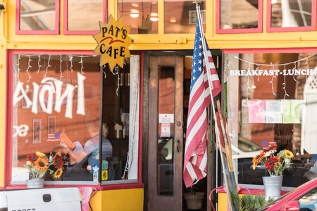 SAN FRANCISCO, CALIFORNIA, USA - OCTOBER 12, 2018: A United States flag in front of the glass of a coffee shop in San Francisco, California, Spain.のeditorial素材