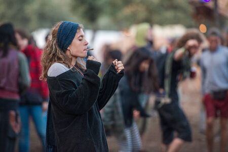 A young woman smoke a joint at the Lost Theory psytransce music festival held in Riomalo de Abajoのeditorial素材