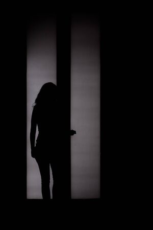 Woman silhouette in front of back-lighted door