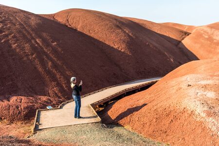 A young woman takes pictures with her smartphone on Paint Cove Trail in Painted Hills
