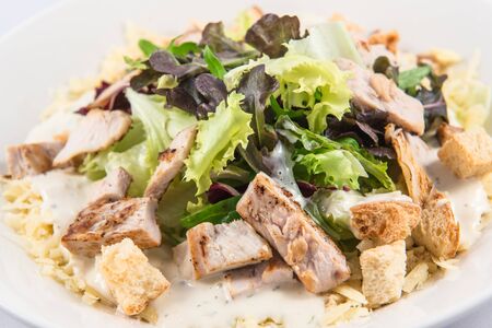 A classic Caesar Salad with mixed vegetables, homemade croutons, parmesan cheese, meat and dressingの写真素材