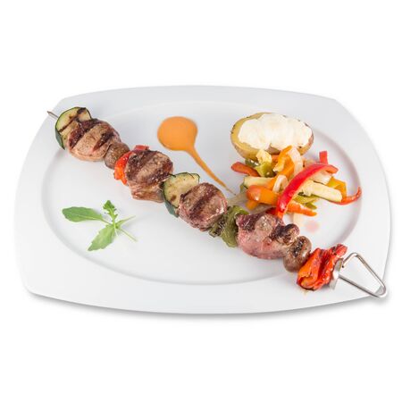 A skewer of iberian pork sirloin with vegetables and baked potatoの写真素材