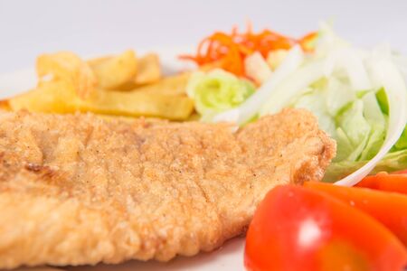 Plate of Roman style hake with chips and salad with lettuce, onion and tomato.の写真素材