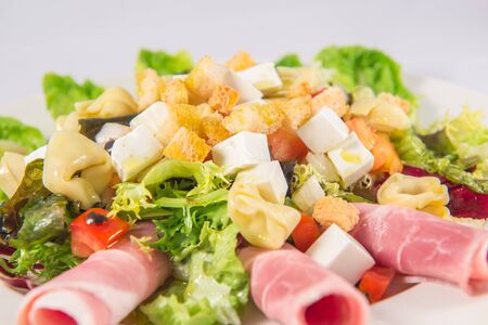 Salad with lettuce, red pepper, tortellini, fresh cheese, tomato, endive , ham and croutonsの写真素材