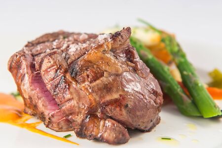 Rare beef tenderloin dish with baked potatoes and green asparagus.の写真素材