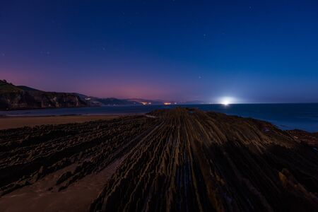 Night view of the flysch with low tide and full moon light in Zumaiaの写真素材