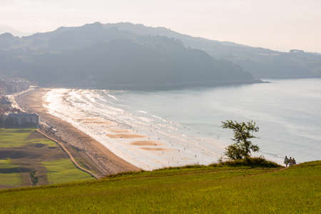 A group of young people with a surfboard returns to the campsite at Zarautz beachのeditorial素材