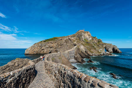 Tourists descend the steps to the hermitage at the top of the island of Gaztelugatxeのeditorial素材