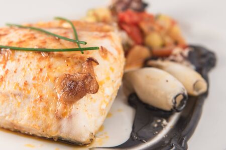 Plate of baked hake with squid in its ink and chives.の写真素材