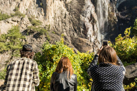 Tourists take pictures with their smartphones from the base of the Bridalveil Fall in Yosemite National Parkのeditorial素材