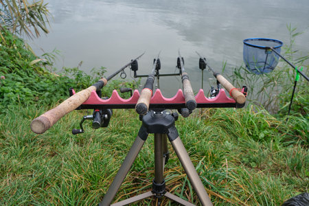 four carp feeder rods on a rod-pod stand with electronic alarms near the lake during the day. back pocket. Fishing, hobbies, outdoor recreationの写真素材