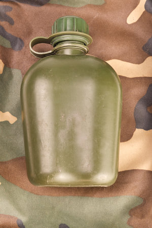 not new army green plastic flask in a prone position on a camouflage background with reflectionの写真素材