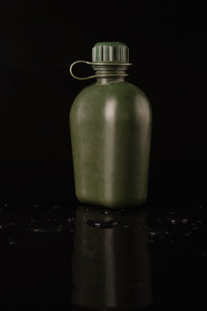 flask plastic army green not new on a black background with reflection and water droplets. side viewの写真素材
