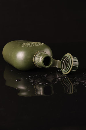 flask plastic army green not new on a black background with reflection and water droplets. opencork. In the supine positionの写真素材