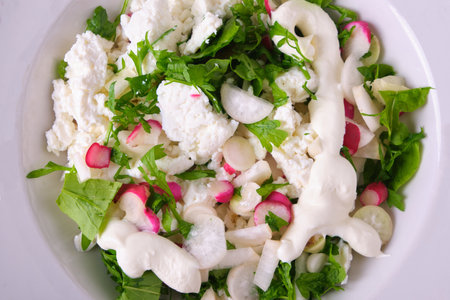Vegetable salad from the garden. Watercress salad and white and red radish cut in a plate with colorful ornament, white cheese and sour cream, isolate, fresh, natural, top viewの写真素材