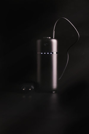 powerbank black on a black background, usb cable, plug, light and reflectionの写真素材