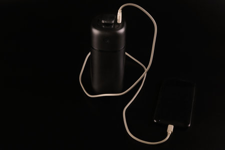 powerbank black on a black background, usb cable, smartphone, plug, light and reflectionの写真素材