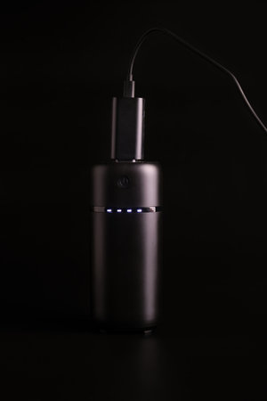 powerbank black on a black background, usb cable, plug, light and reflectionの写真素材