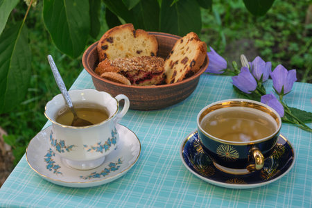 mint tea outdoors in mugs, cookies and cupcakes in a plate, flowersの写真素材