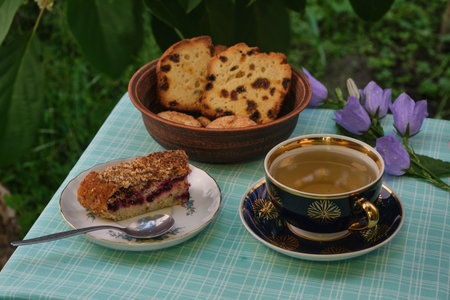 mint tea outdoors in a mug, cake, cookies and a cupcake in a plate, flowersの写真素材