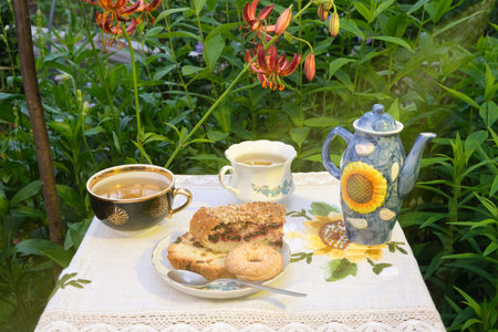 mint tea outdoors in mugs, cookies and cupcakes in a plate, lilia flowersの写真素材