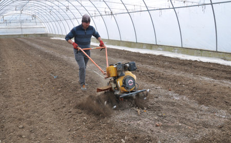 Chortkiv - Ternopil - Ukraine - March 18, 2019. Preparation of soil in the greenhouse for planting vegetable crops using a mini tractor in an agricultural enterprise in Chortkiv districtのeditorial素材