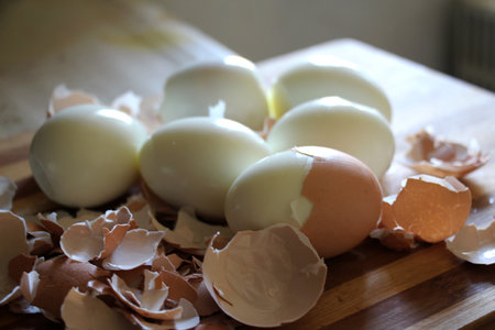 On the kitchen board, hard-boiled chicken eggs are peeled