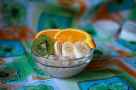oatmeal, orange, banana, kiwi on wooden boardの写真素材