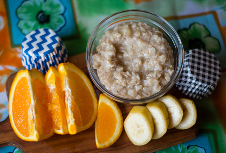 oatmeal, orange, banana on wooden boardの写真素材