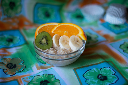 oatmeal, orange, banana, kiwi on wooden boardの写真素材
