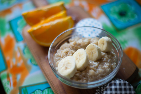 oatmeal, orange, banana, kiwi on wooden boardの写真素材